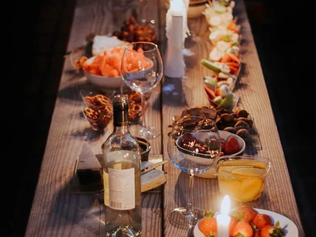A long wooden table set with shared plates, wine, and candles