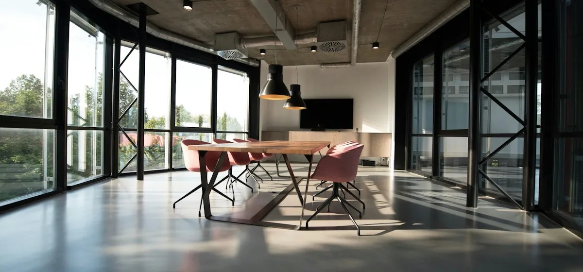 Open workspace with long tables beside floor-to-ceiling windows