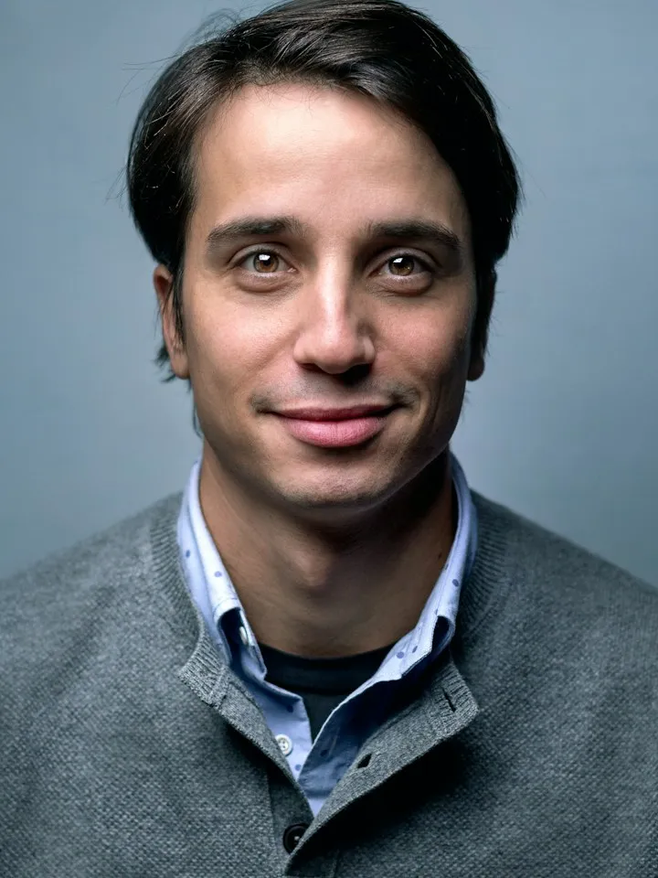 Portrait of a man in a grey sweater against a blue backdrop