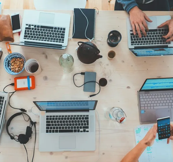 Overhead view of people working on laptops at a shared table