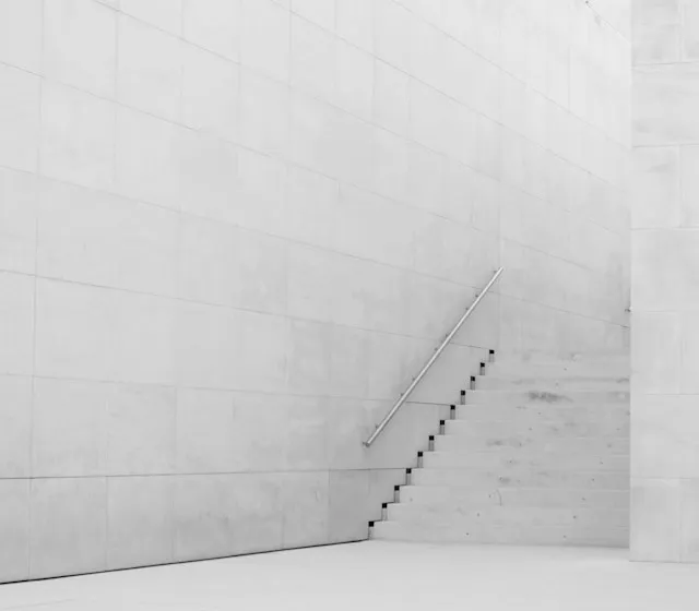 Concrete stairs rising along a pale white wall