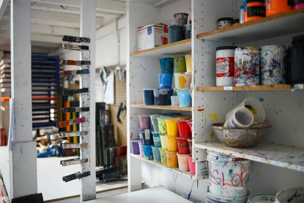 Pottery studio shelves with glaze buckets and finished pieces
