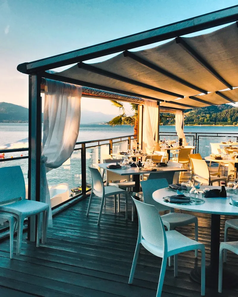 Terrace restaurant with set tables above a lake at dusk