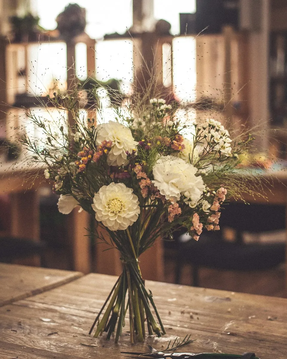 A loose arrangement of cream and peach flowers on a restaurant table