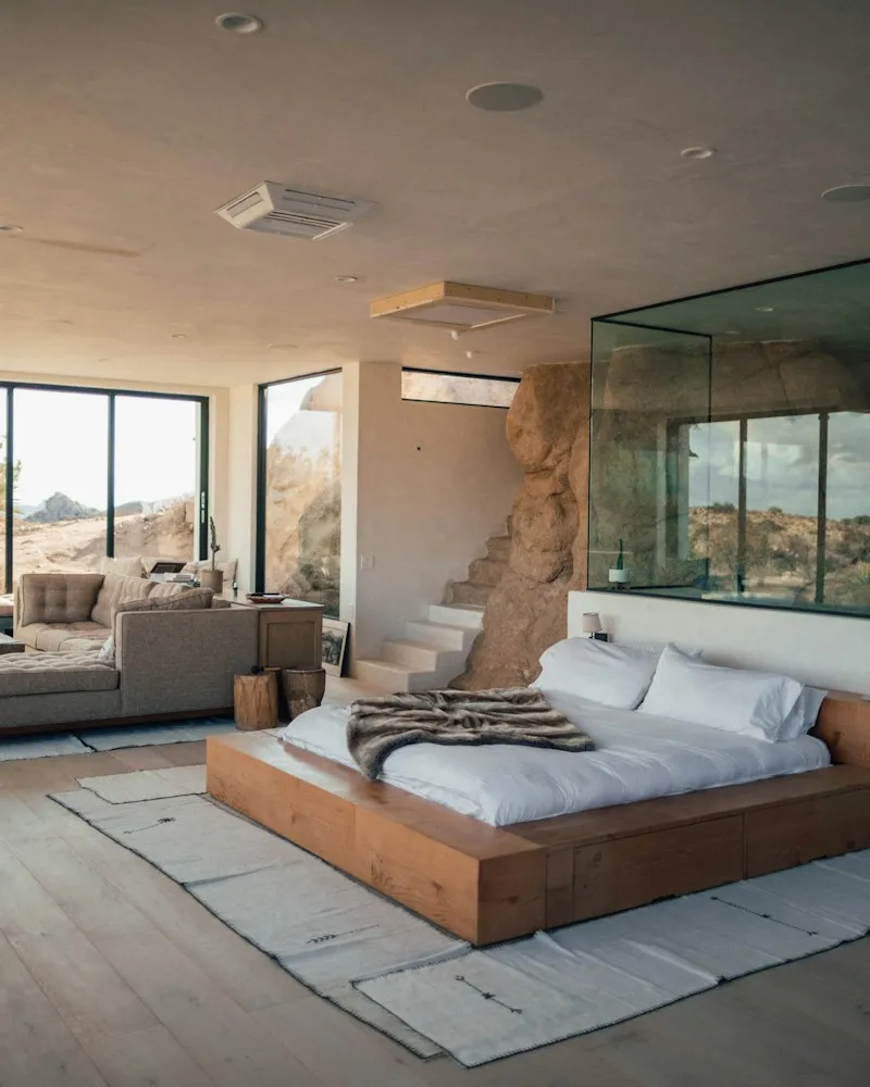 Hotel bedroom with a low wooden bed and tall windows