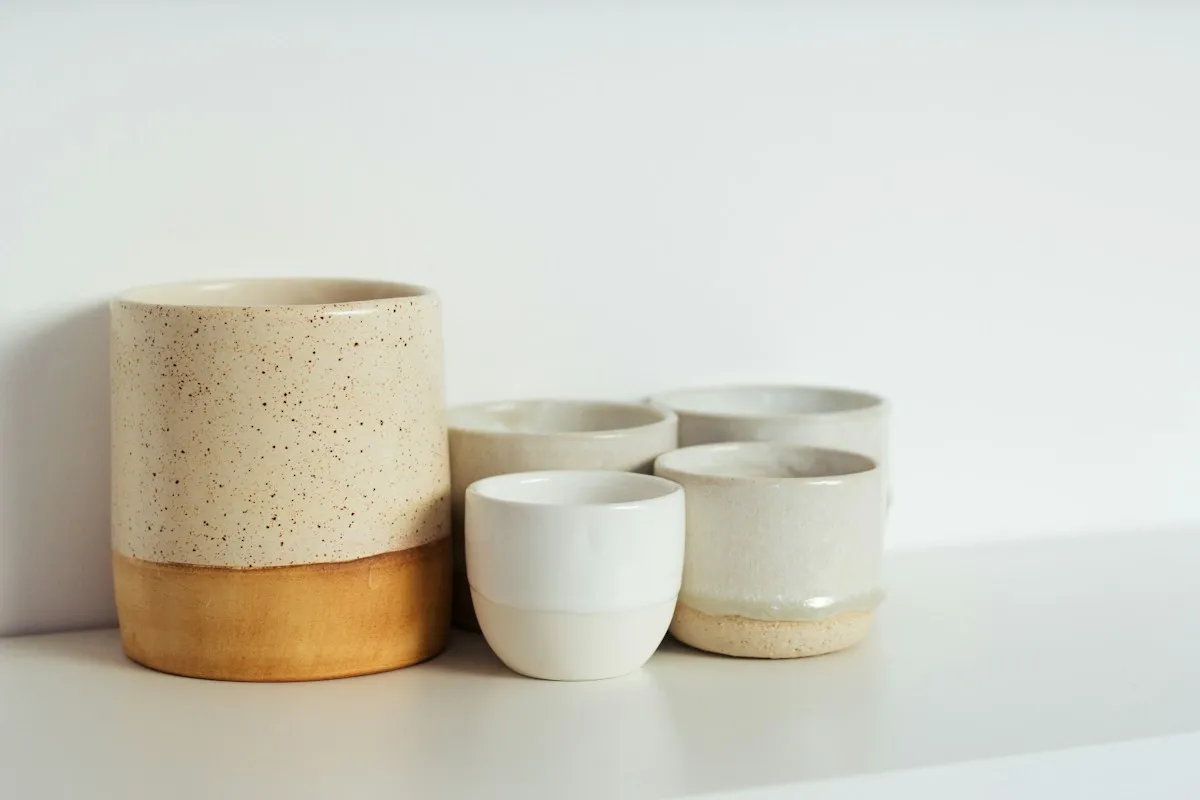 Stoneware cups in white and speckled glazes on a white shelf