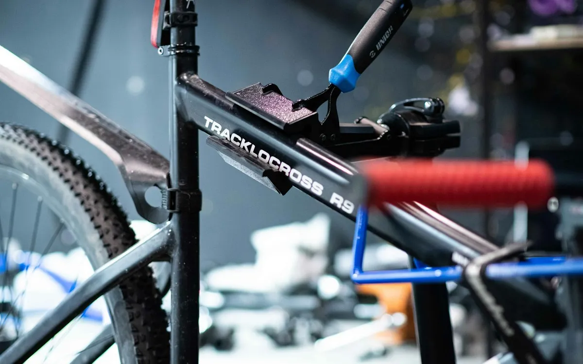 A bicycle clamped in a workshop repair stand with tools on the wall behind