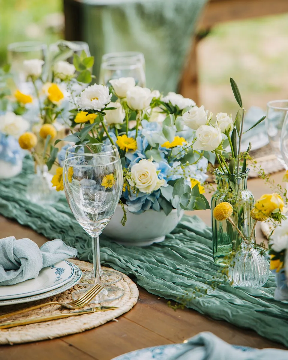 A reception table set with small arrangements of yellow and white flowers