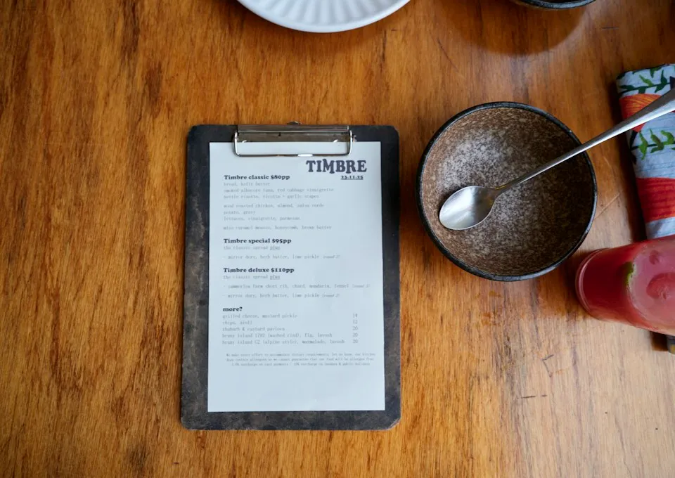 Printed menu on a clipboard beside a bowl on a wooden table