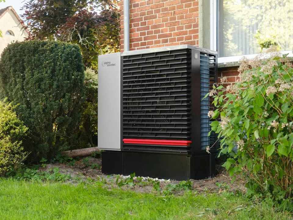 An outdoor heat pump beside the brick wall of a family home